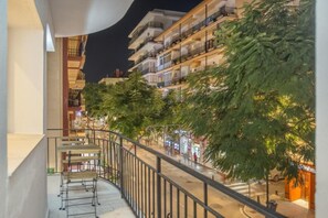 Un immeuble à plusieurs étages doté de balcons, une rue piétonne et des arbres.