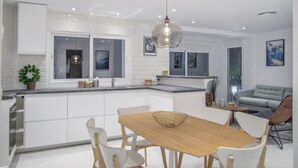 Una cocina moderna con armarios blancos, una mesa de comedor de madera y una lámpara colgante.