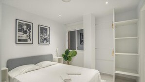 Un dormitorio moderno con cama, dos cuadros enmarcados, una planta en la mesita de noche y un vestidor.