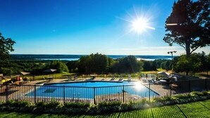Une piscine avec vue sur l’océan, entourée d’une clôture et de verdure.