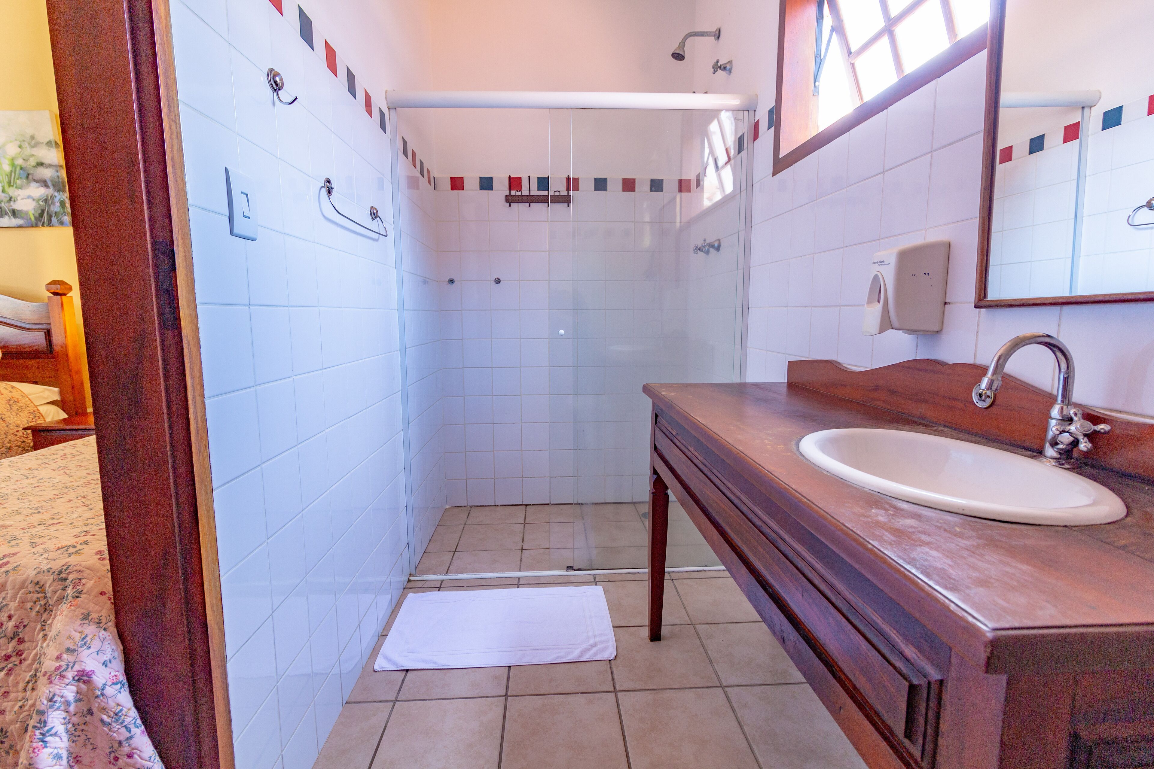A bathroom with a wooden vanity, a sink, and a shower area.