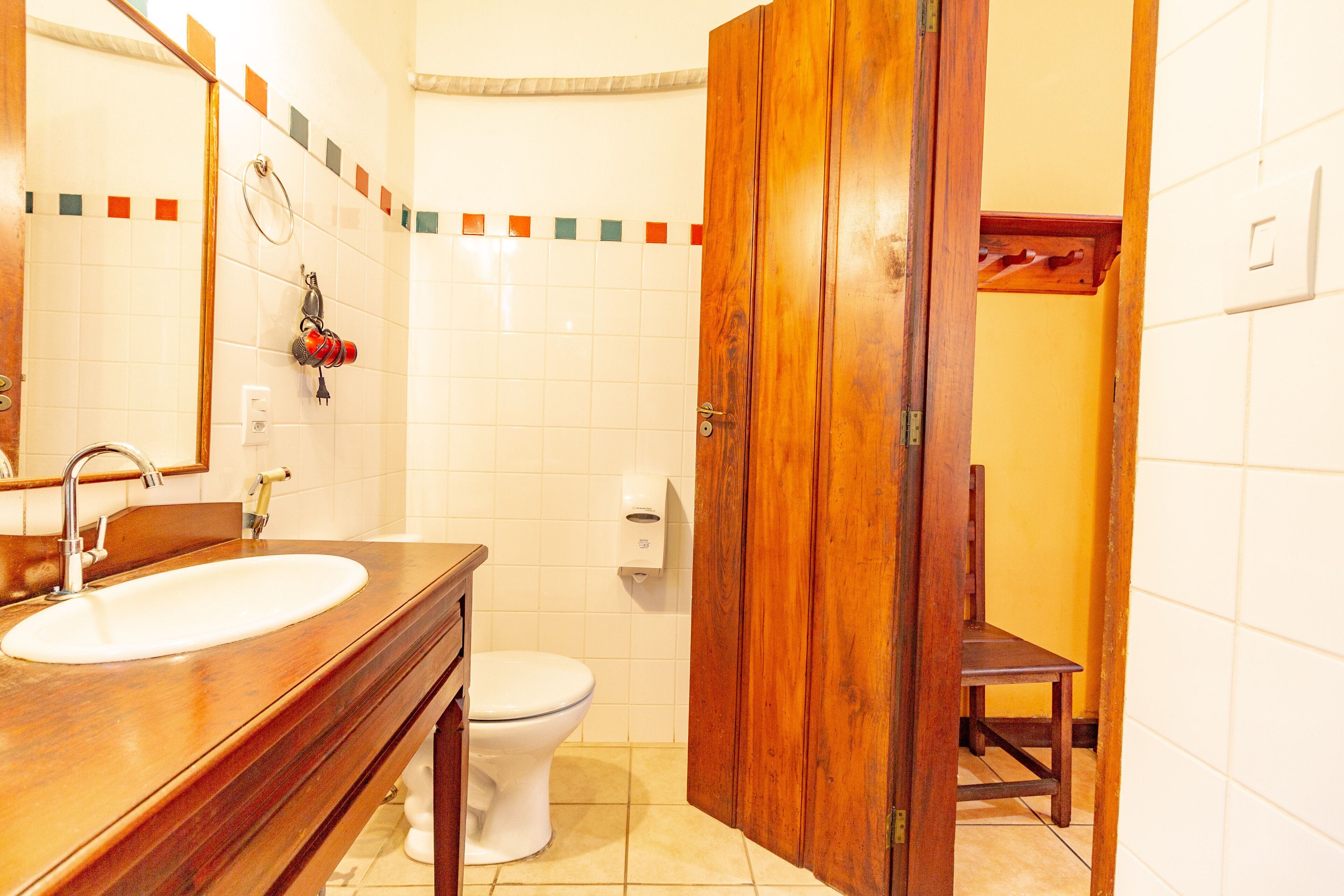 A bathroom with a wooden vanity, a white sink, a toilet, and a wooden door.