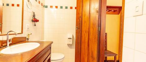 A bathroom with a wooden vanity, a white sink, a toilet, and a wooden door.