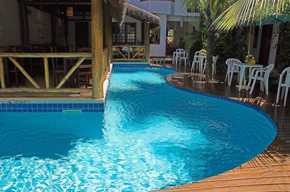 A swimming pool with a wooden deck and white plastic chairs. - Pousada Laguna Blue (Paraty)