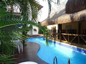 A pool area with a wooden deck, a thatched-roof structure, and outdoor seating. - Pousada Laguna Blue (Paraty)