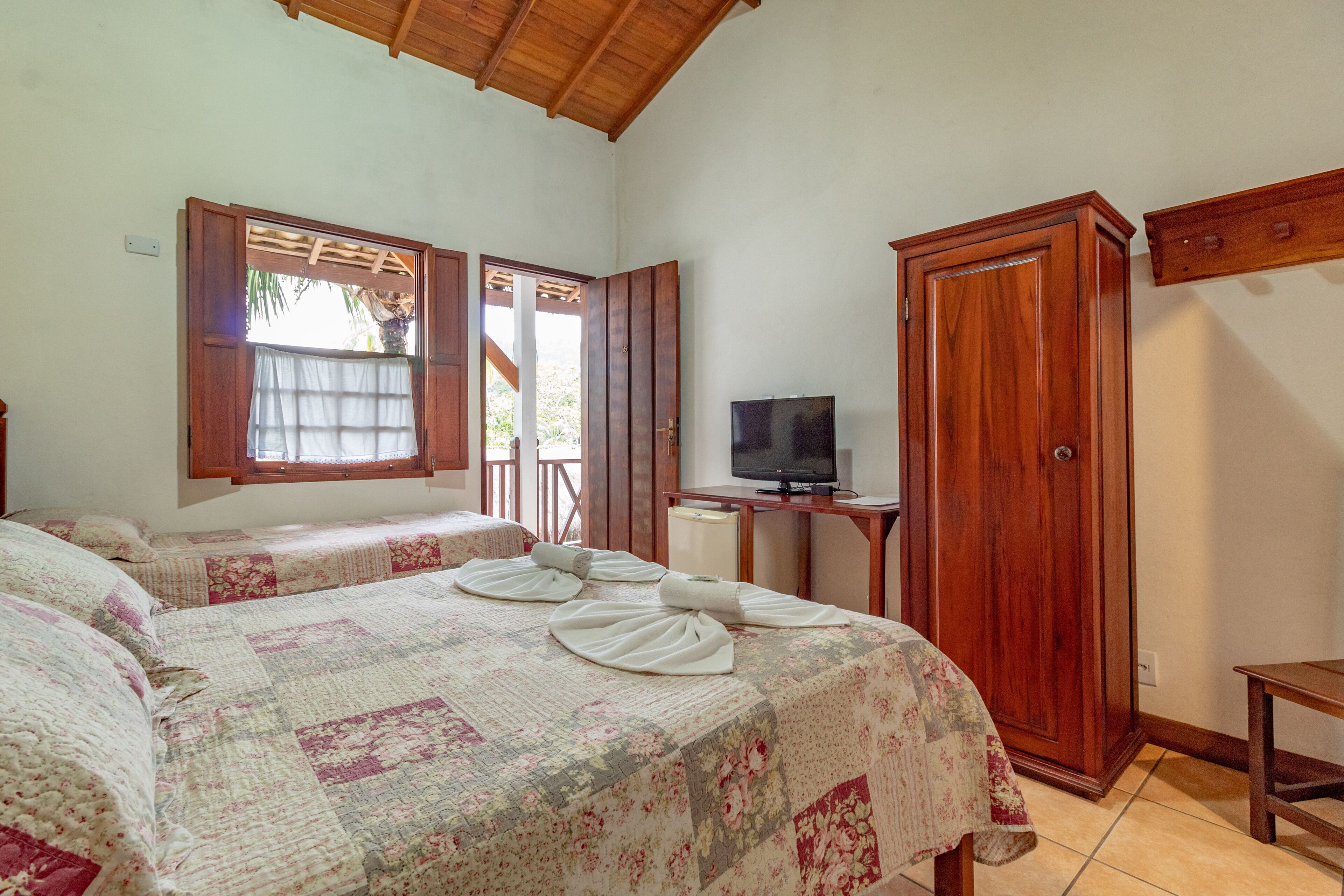 Un dormitorio con dos camas, un televisor sobre una mesita y un armario.