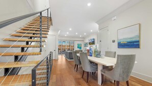 Un interior moderno con una escalera, comedor y obras de arte.