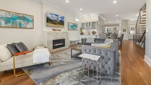 Un salón espacioso con chimenea, un sofá gris, una mesa de centro y una escalera.