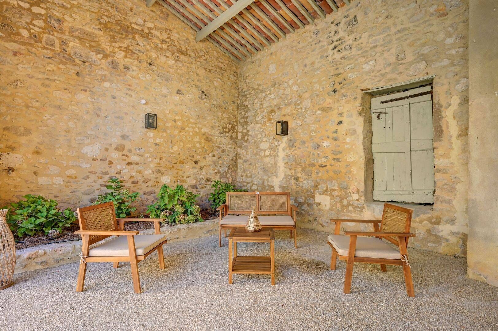 A rustic stone interior with wooden furniture and a window with shutters.
