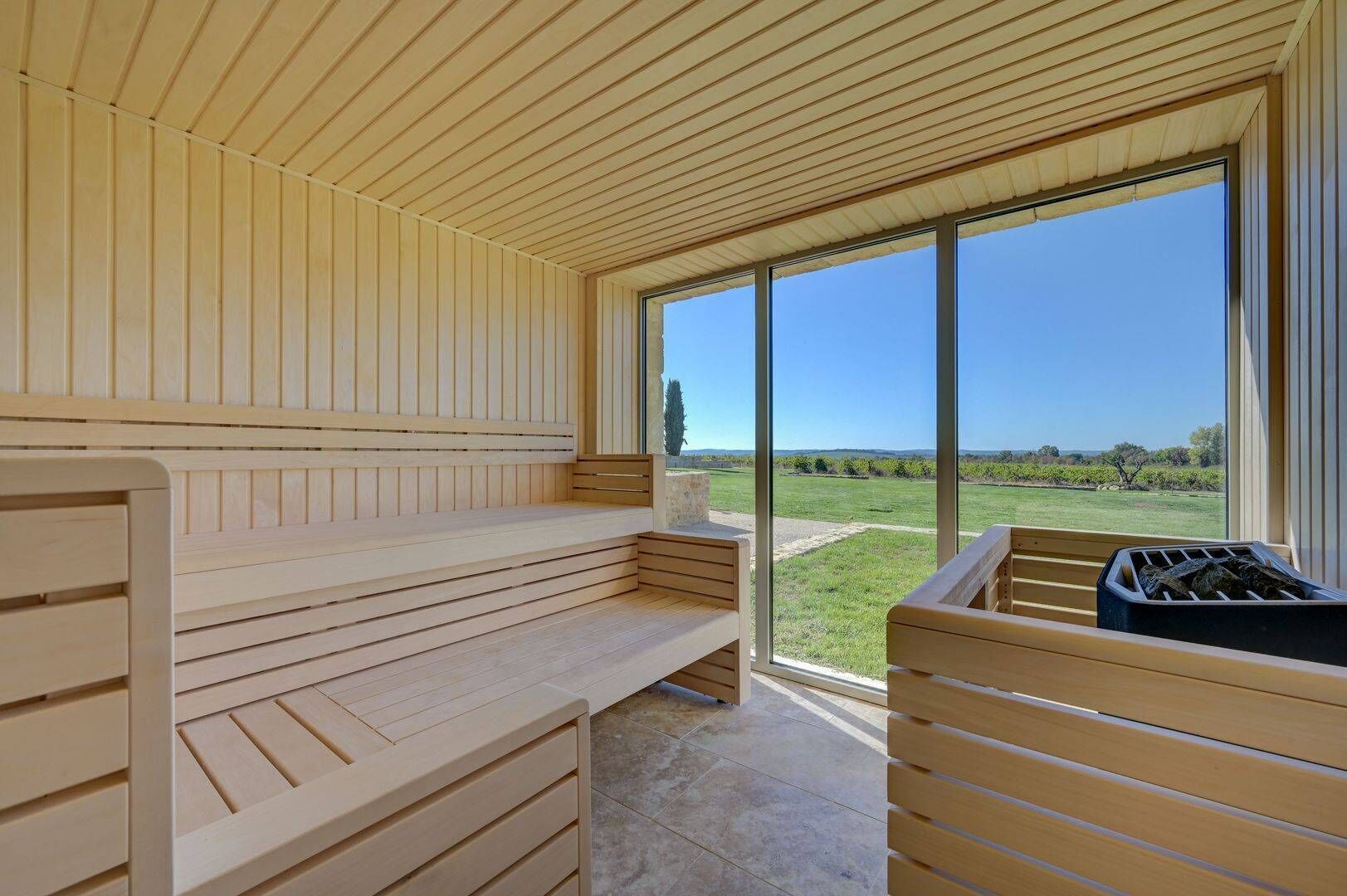 Un sauna avec des bancs en bois et une grande fenêtre donnant sur un vignoble.