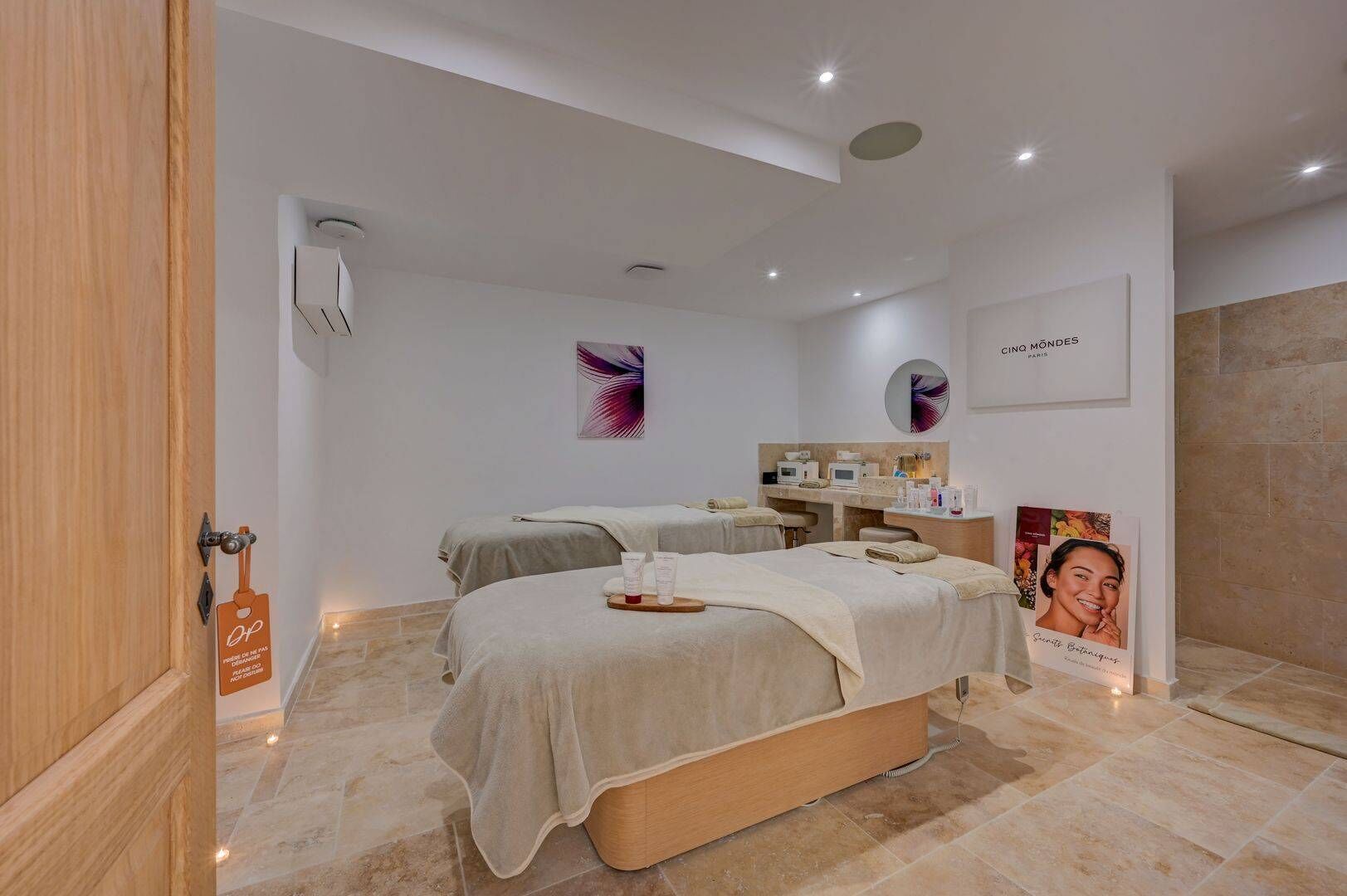 Un moderno spa con dos camas, una mesa de masaje y un tocador con artículos de aseo.