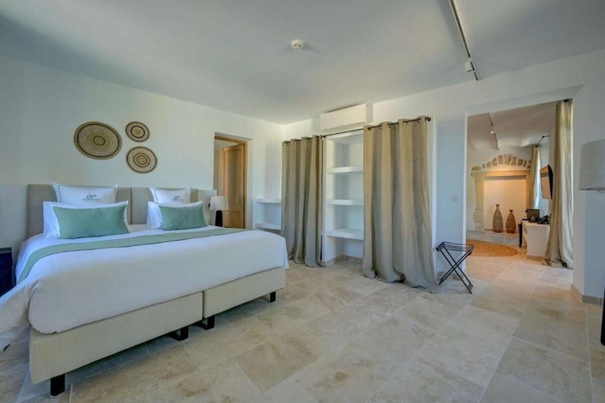 A bedroom with a bed, curtains, shelves, and a small table.