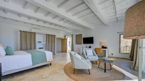 A modern hotel room with a bed, two armchairs, a small table, a TV, and a balcony with a view. - Domaine de Privadière & Spa (Garrigues-Sainte-Eulalie)