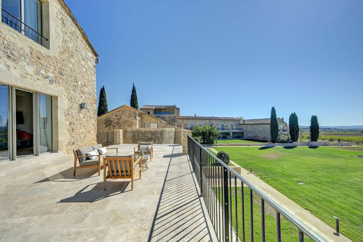Un bâtiment en pierre doté d’un patio aménagé avec du mobilier d’extérieur et offrant une vue sur un vignoble.