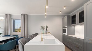 A modern kitchen with a central island, grey cabinets, and a dining area with blue chairs. - Villa Villa Contessina (Istria - Novigrad) (Novigrad)