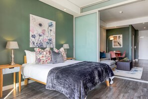 A modern bedroom with a large bed, a desk, and a chair.