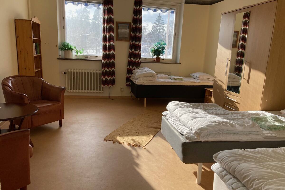 Ein Schlafzimmer mit Bett, Stuhl, Kleiderschrank und einem Fenster mit Vorhängen.