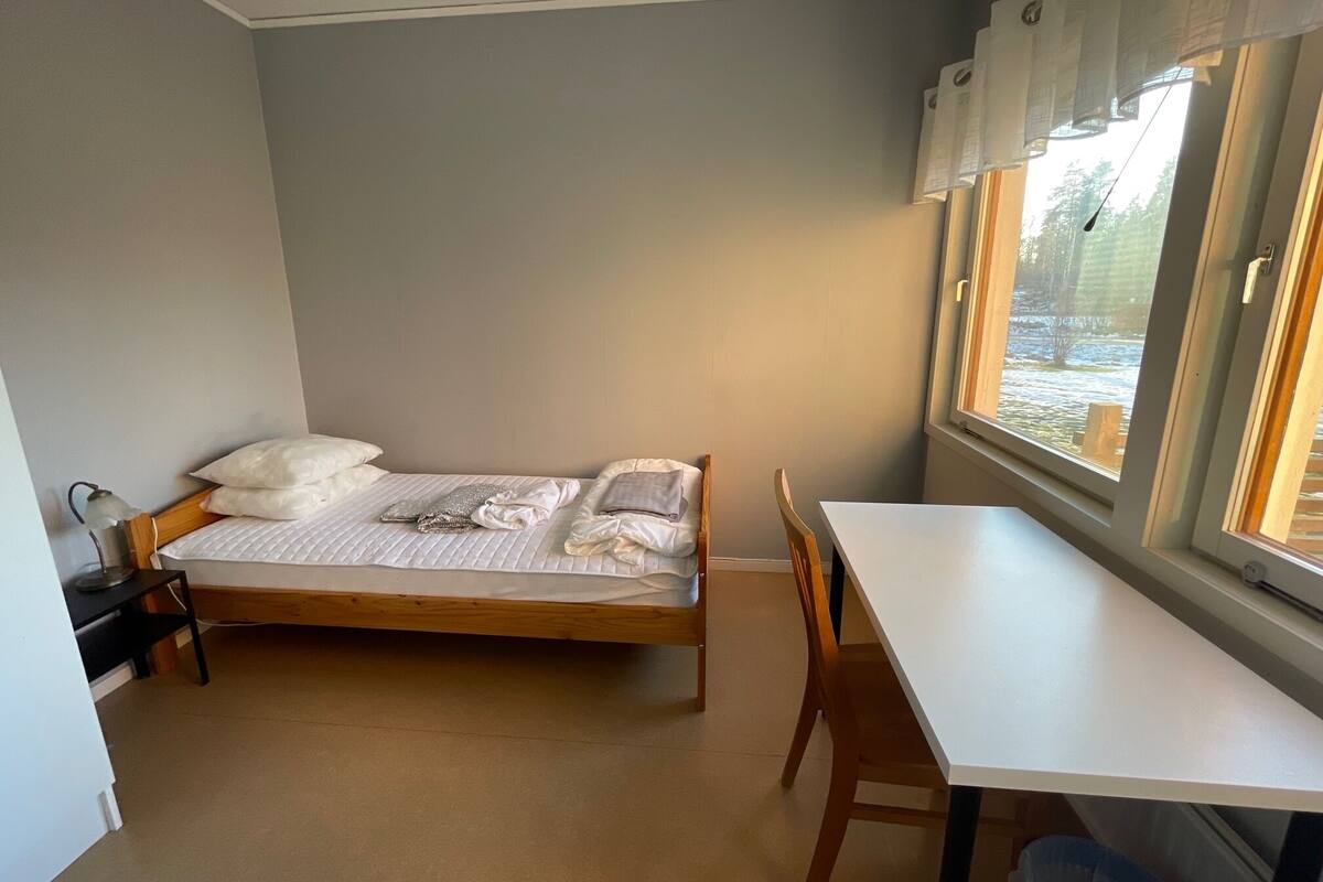 Ein Schlafzimmer mit Bett, Schreibtisch und Fenster.