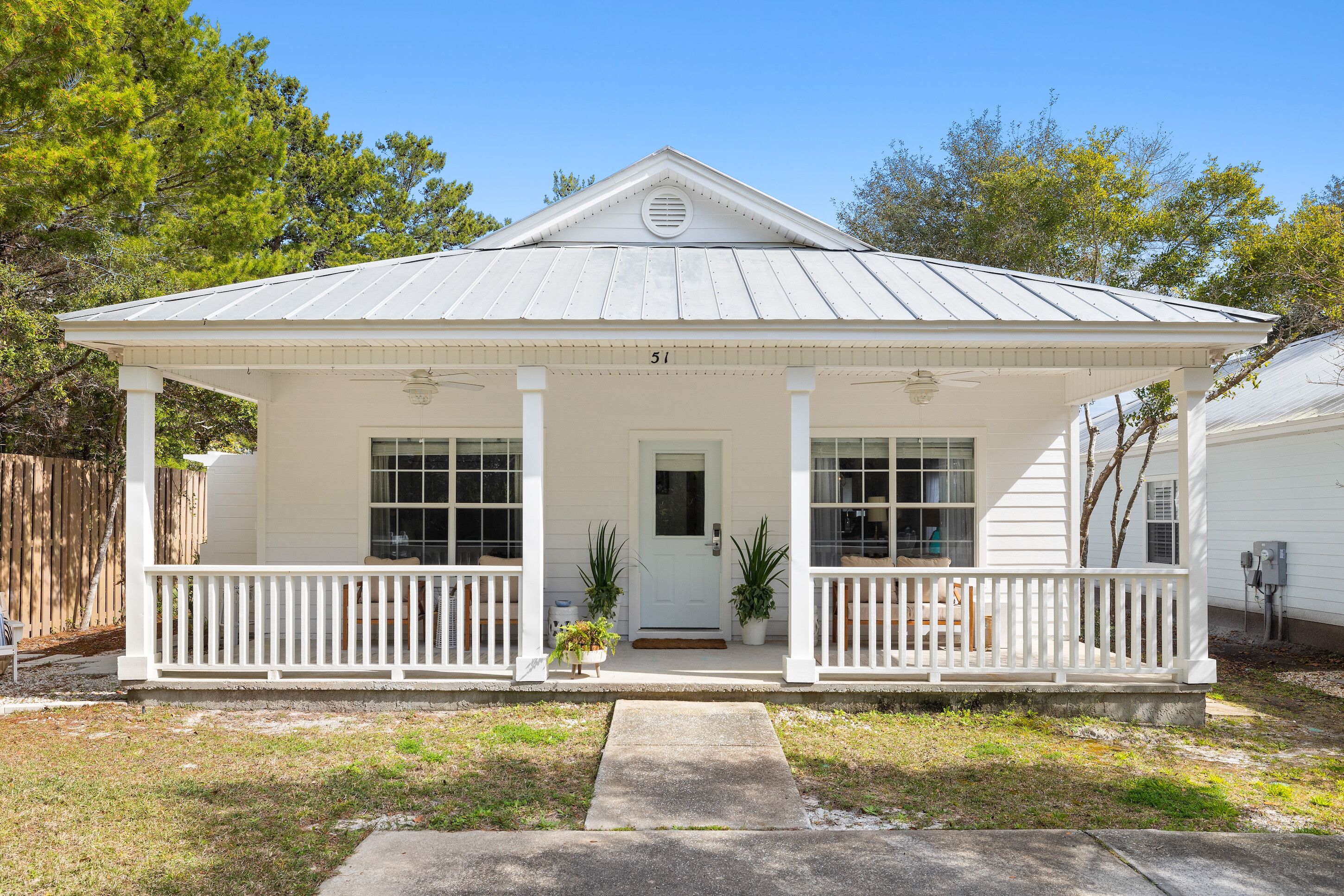 A white single-story house with a front porch, a number '51' above the door, and a small front yard.