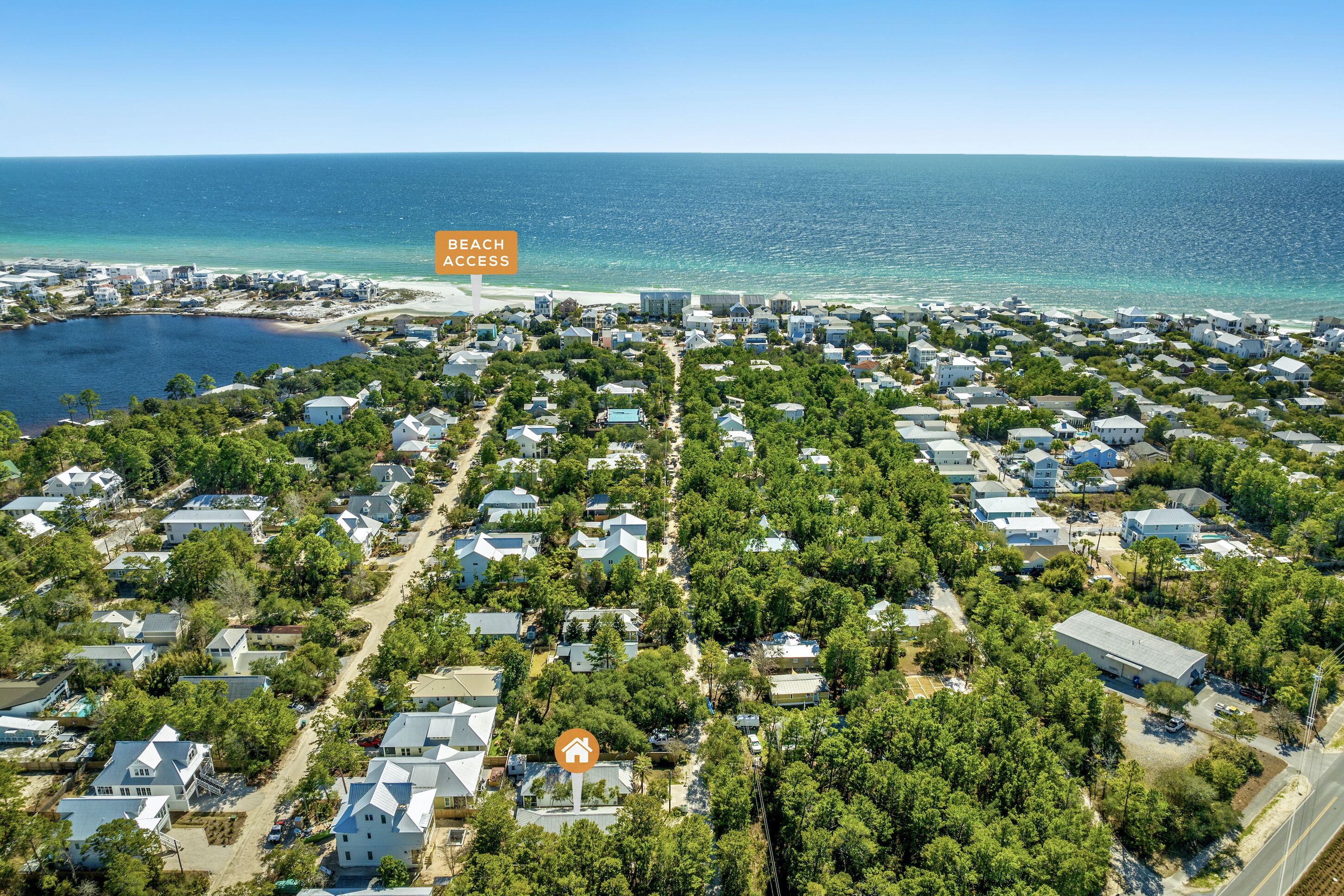 An aerial view of a residential area with houses, a beach, and a marina.
