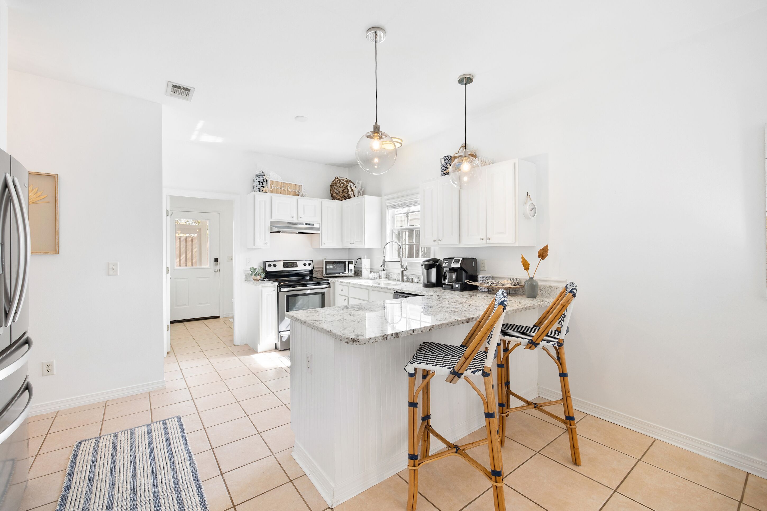 A modern kitchen with white cabinets, a central island, and two bar stools.