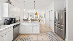 A modern kitchen with white cabinetry, stainless steel appliances, and pendant lighting.