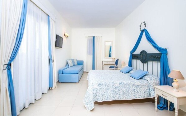 A bedroom with a bed, a nightstand, a dresser, a mirror, and a blue canopy bed.