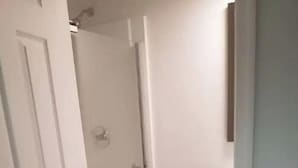 En smal hall med en glasdörr som leder till en duschhörna.