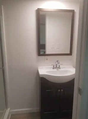 A bathroom with a white sink, a mirror above it, and a dark cabinet below.