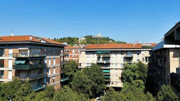 Un immeuble résidentiel à plusieurs étages, doté de balcons, entouré d’arbres et surplombant un ciel bleu clair.