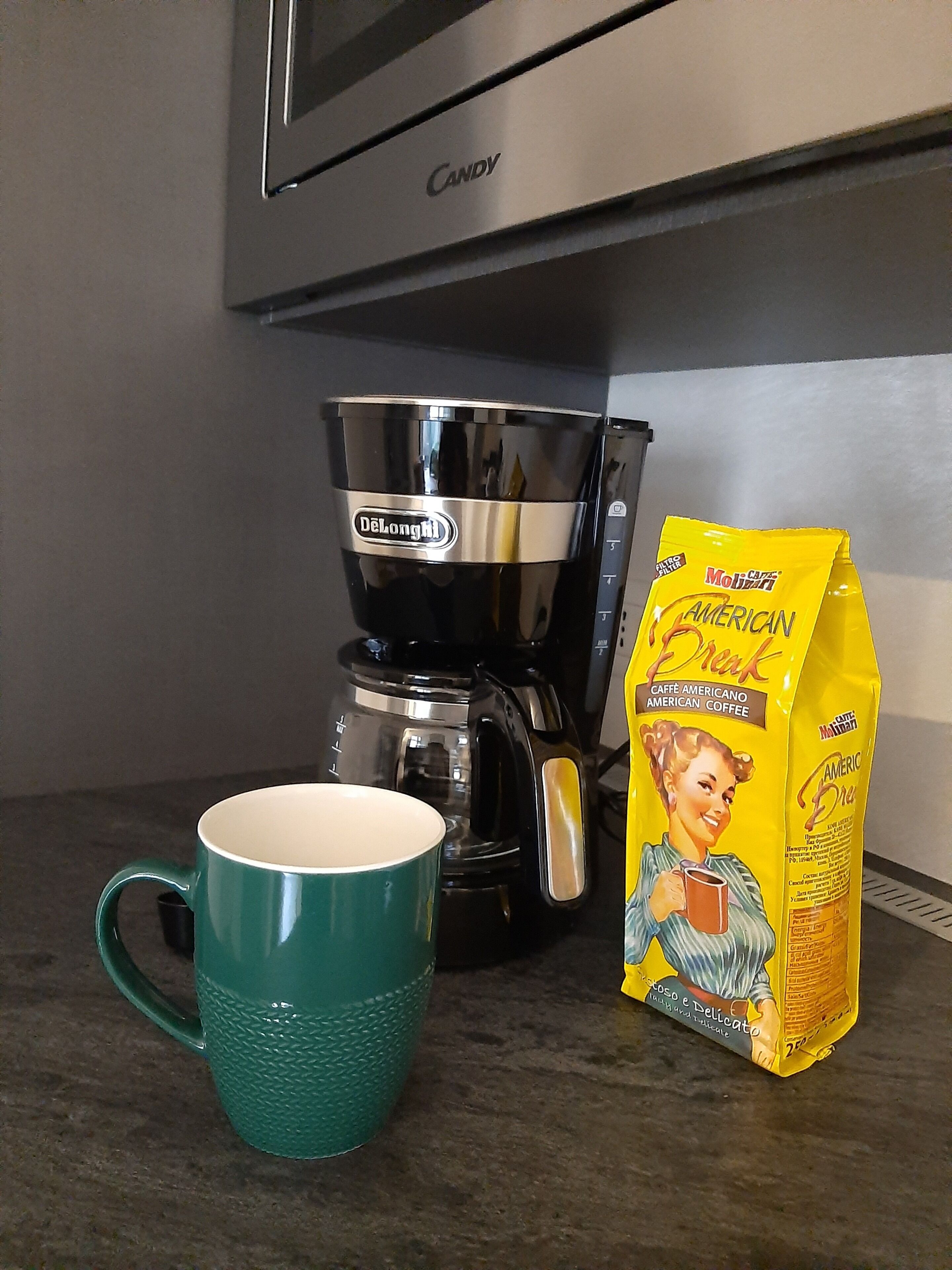 Una encimera de cocina con una cafetera, una taza y un paquete de café.