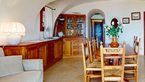 Un salon chaleureux avec un coin repas, des meubles en bois et une cuisine équipée d’armoires et d’un évier.