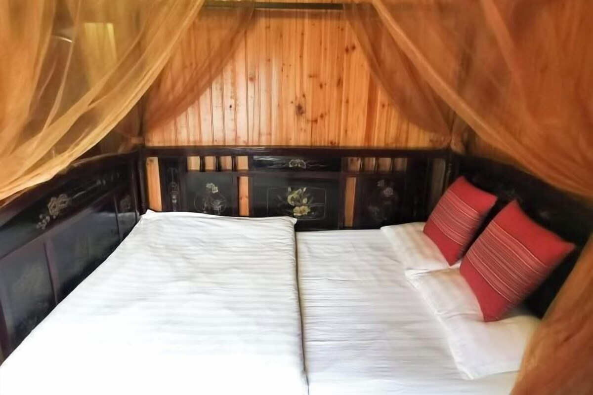 A bed with white and red bedding, wooden headboard, and a canopy.