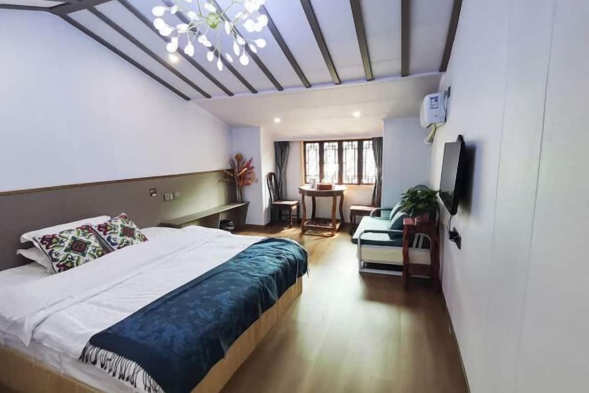 Hotellihuone, jossa on sänky, työpöytä, tuoli, televisio ja ikkuna, jossa on verhot.