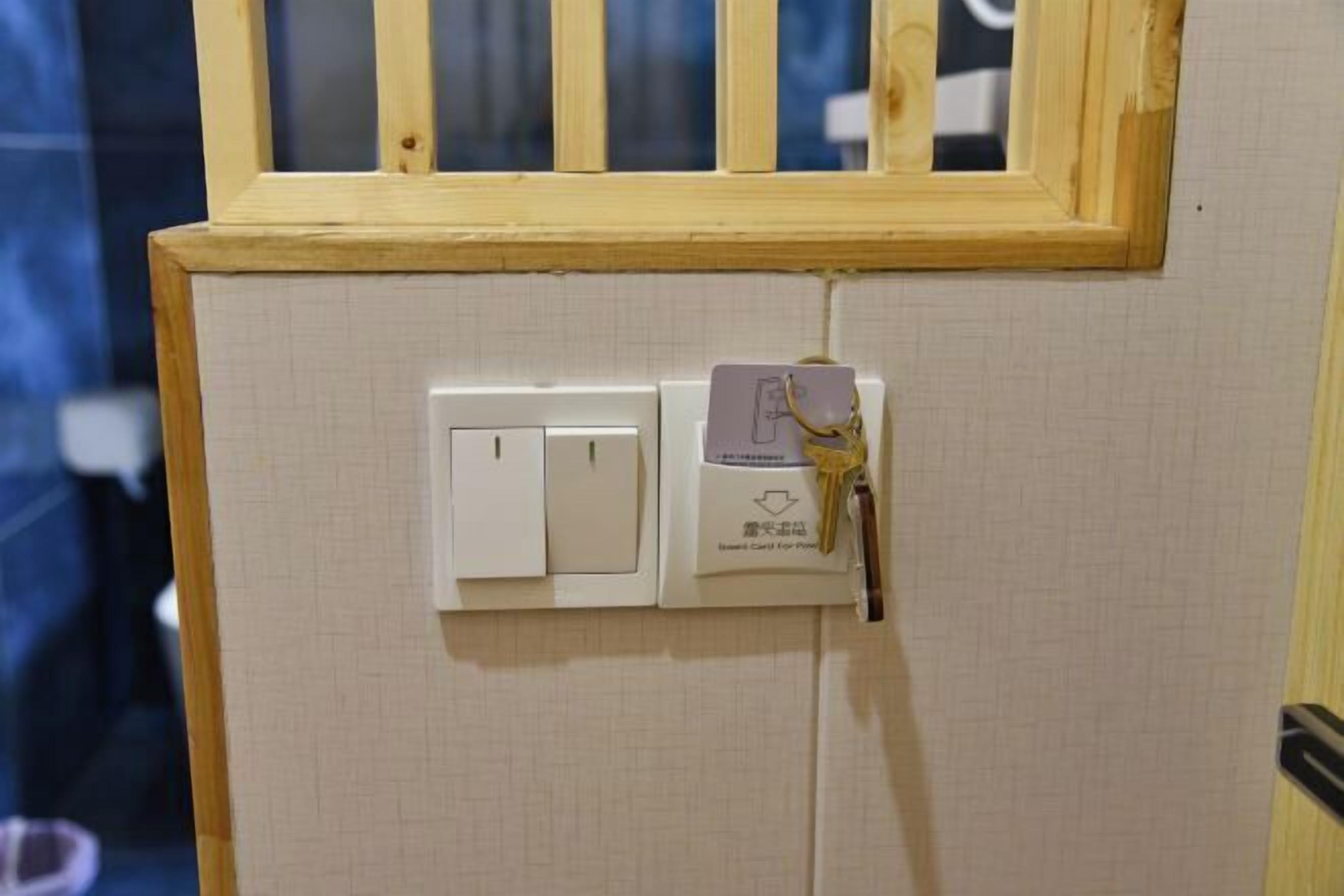 A wall-mounted light switch and a keycard holder with a key.