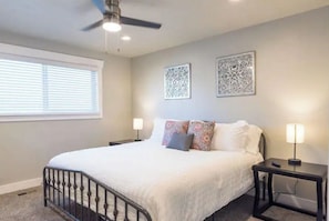 A bedroom with a bed, two wall-mounted lamps, a ceiling fan, and decorative wall art.