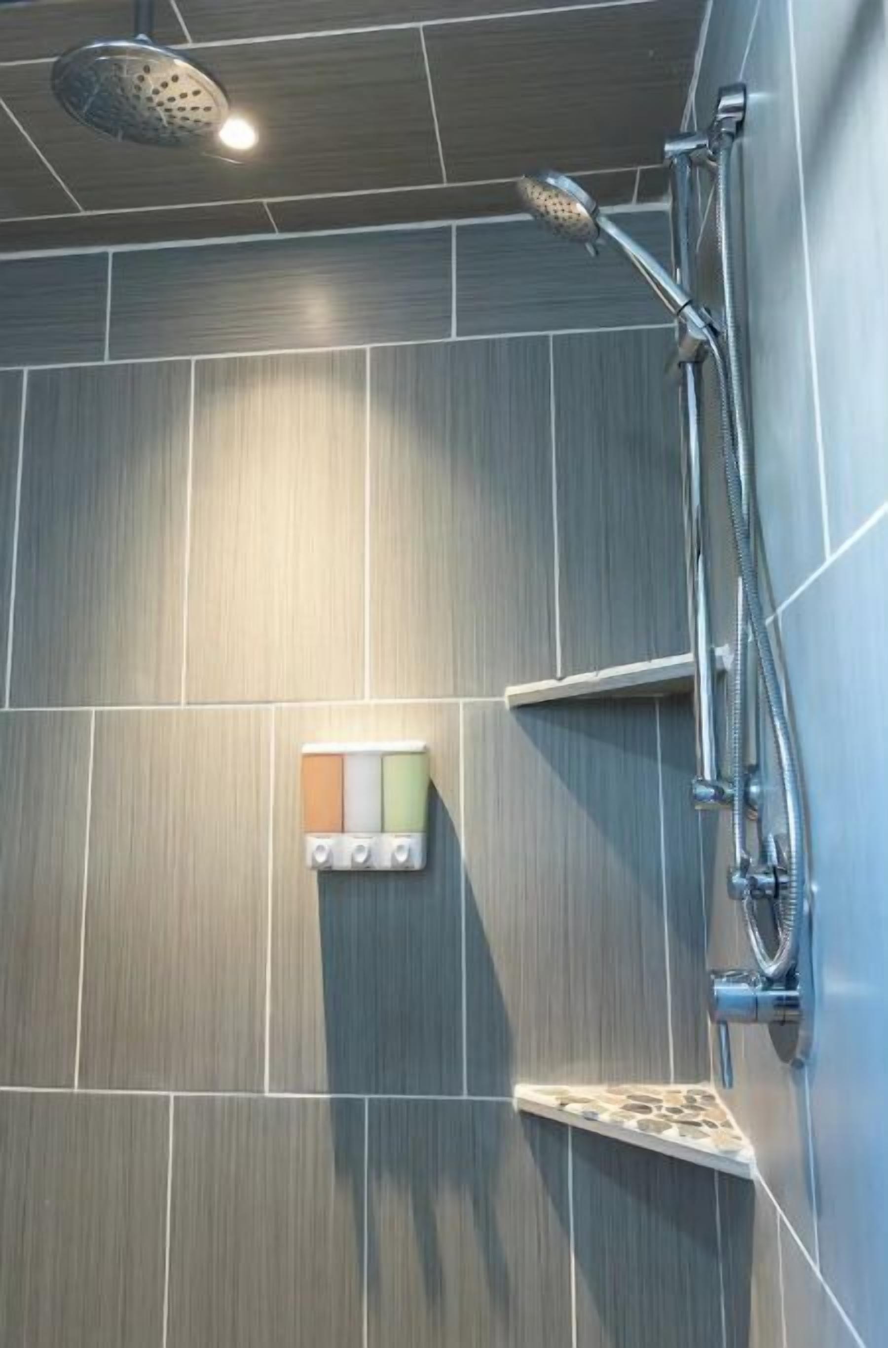 A modern shower with a handheld showerhead and a wall-mounted faucet.