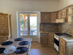Una cocina con armarios de madera, salpicadero de azulejos y un comedor con una mesa para dos.