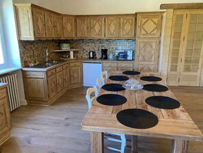 Una cocina con armarios de madera, lavavajillas integrado y una mesa de comedor con posavasos negros.