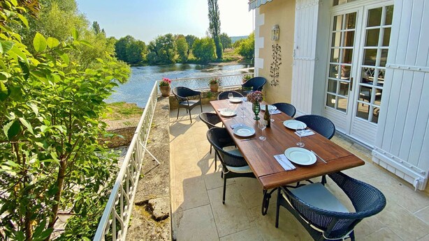 Un espace de restauration en plein air offrant une vue sur une rivière, entouré de verdure.