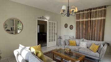 A living room with a grey sofa, a coffee table, a chandelier, and a patterned rug.