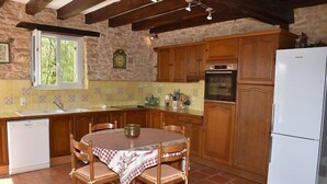 A rustic kitchen with wooden cabinets, a white refrigerator, and a dining table with chairs.