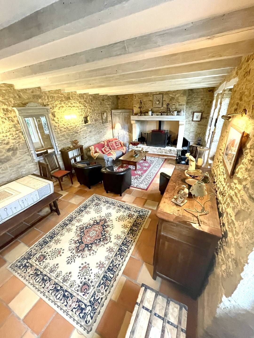 Une pièce rustique aux murs de pierre, dotée d’une cheminée, d’un canapé, d’une table basse et d’un tapis à motifs.