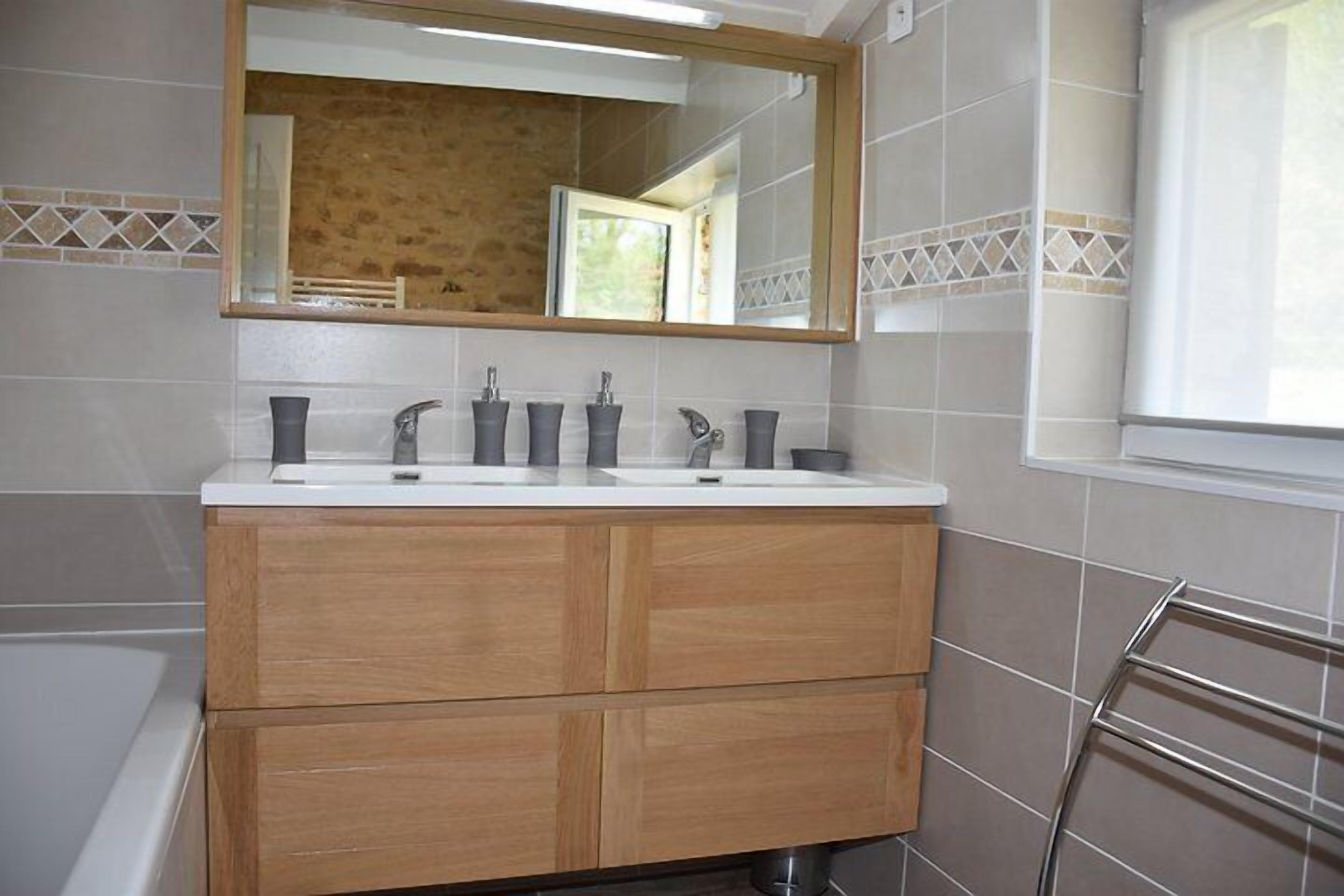 A bathroom with a wooden vanity, two sinks, and a large mirror.