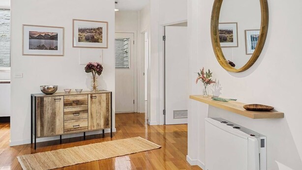 A modern interior with a wooden cabinet, a mirror, and framed pictures on the wall.
