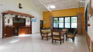 A reception area with a counter, wooden chairs, and a tiled floor. - Hotel Sunrise Guamal (Guamal)