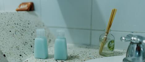 A bathroom sink with two bottles of liquid soap and a bottle of reed diffuser.