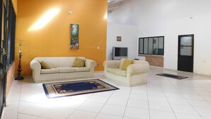 A spacious living area with two sofas, a TV, and a decorative painting on the wall. - Hotel Sunrise Guamal (Guamal)