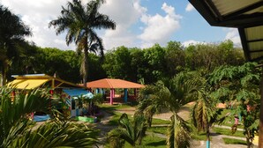 A courtyard with palm trees, a pathway, and colorful buildings. - Hotel Sunrise Guamal (Guamal)