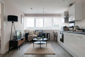 Uma sala de estar moderna com sofá, mesa de centro e televisão sobre um suporte.